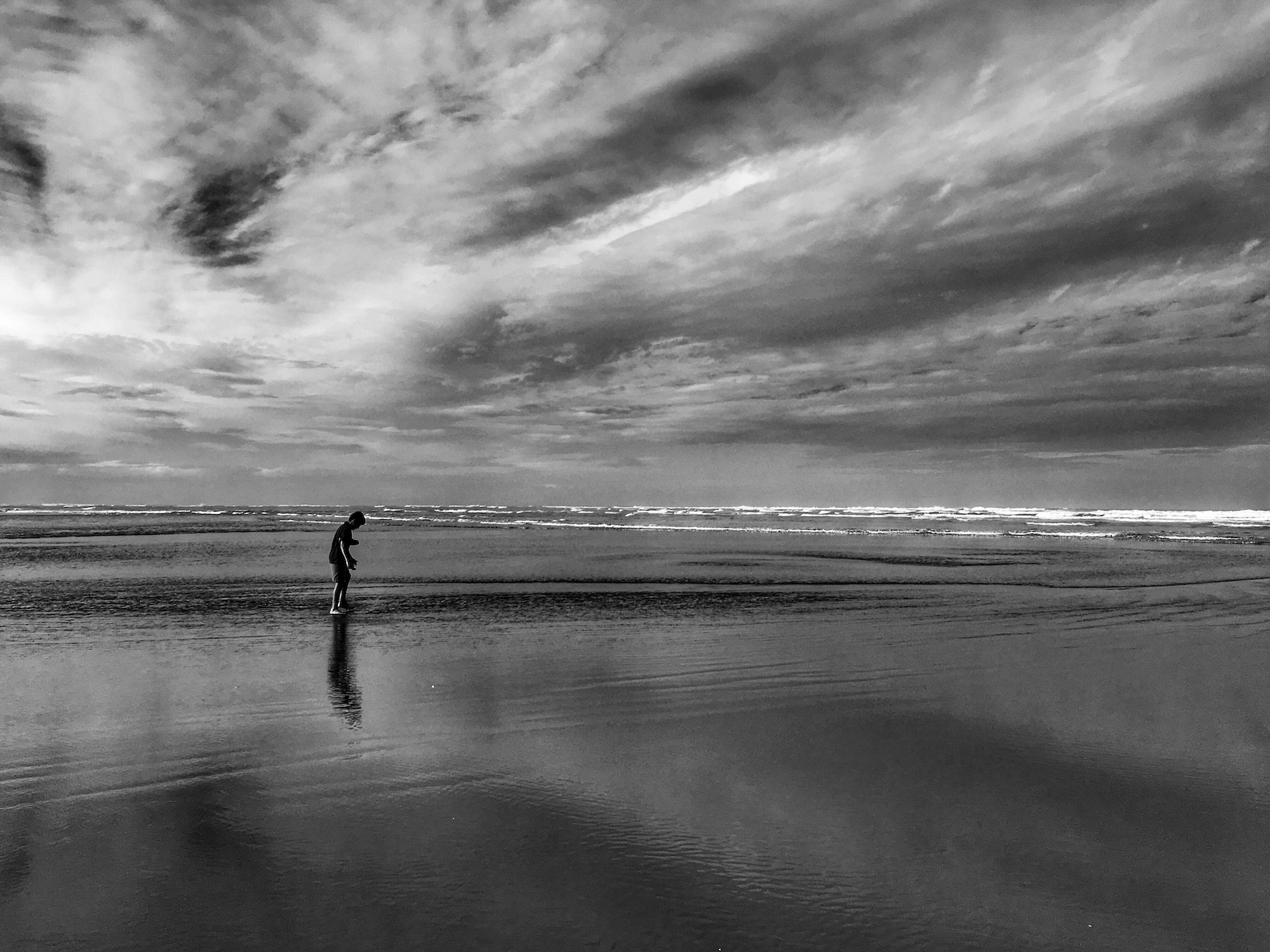 Child walking on the beach on a cloudy day.