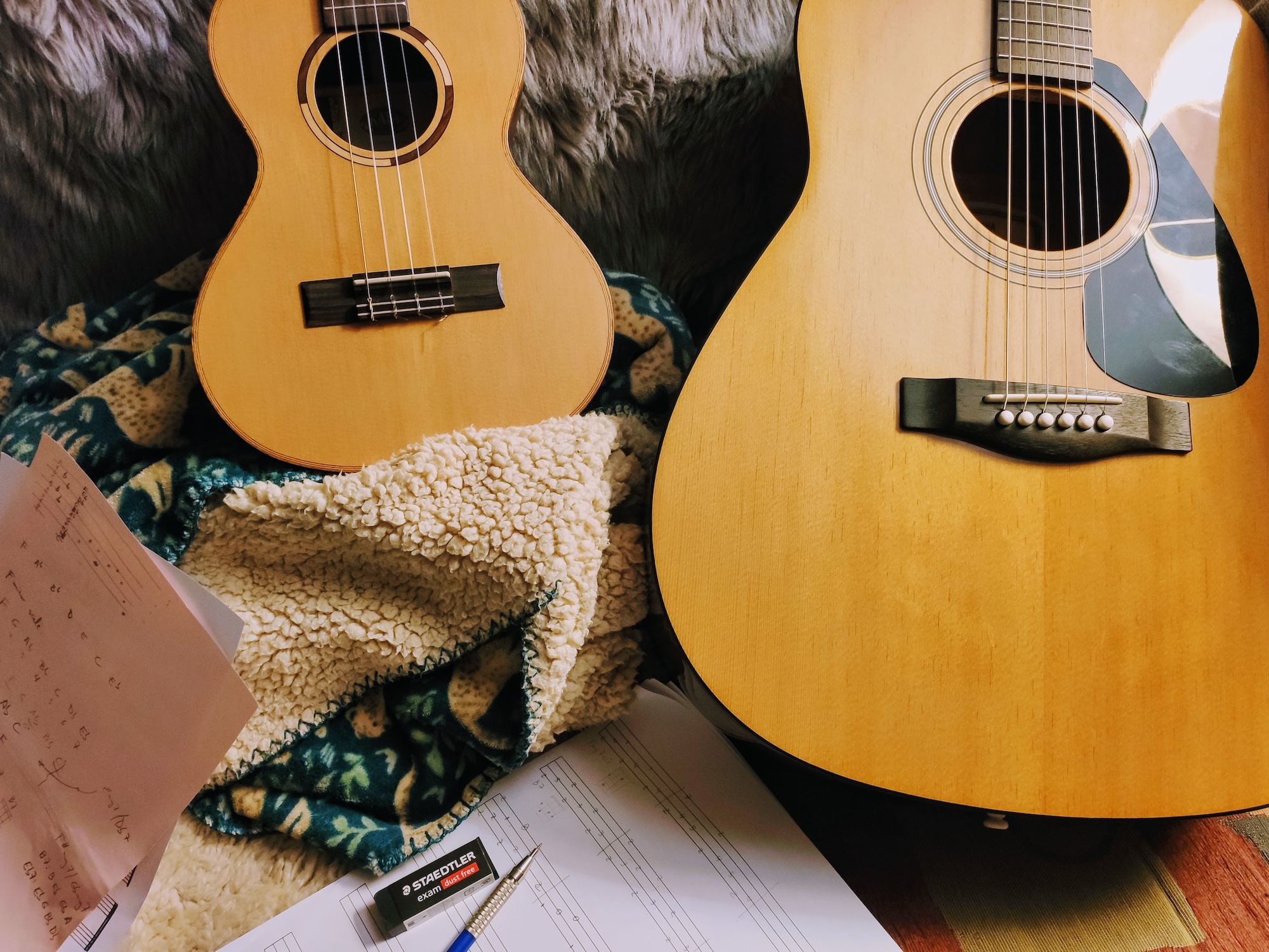 Low-G ukulele and guitar, together with some music sheets.